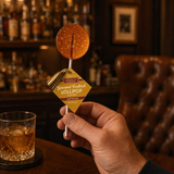 Hand holding an Old Fashioned bourbon lollipop with hang tag
