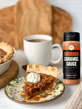 Bourbon Caramel Sauce bottle next to pecan pie with caramel and a cup of coffee